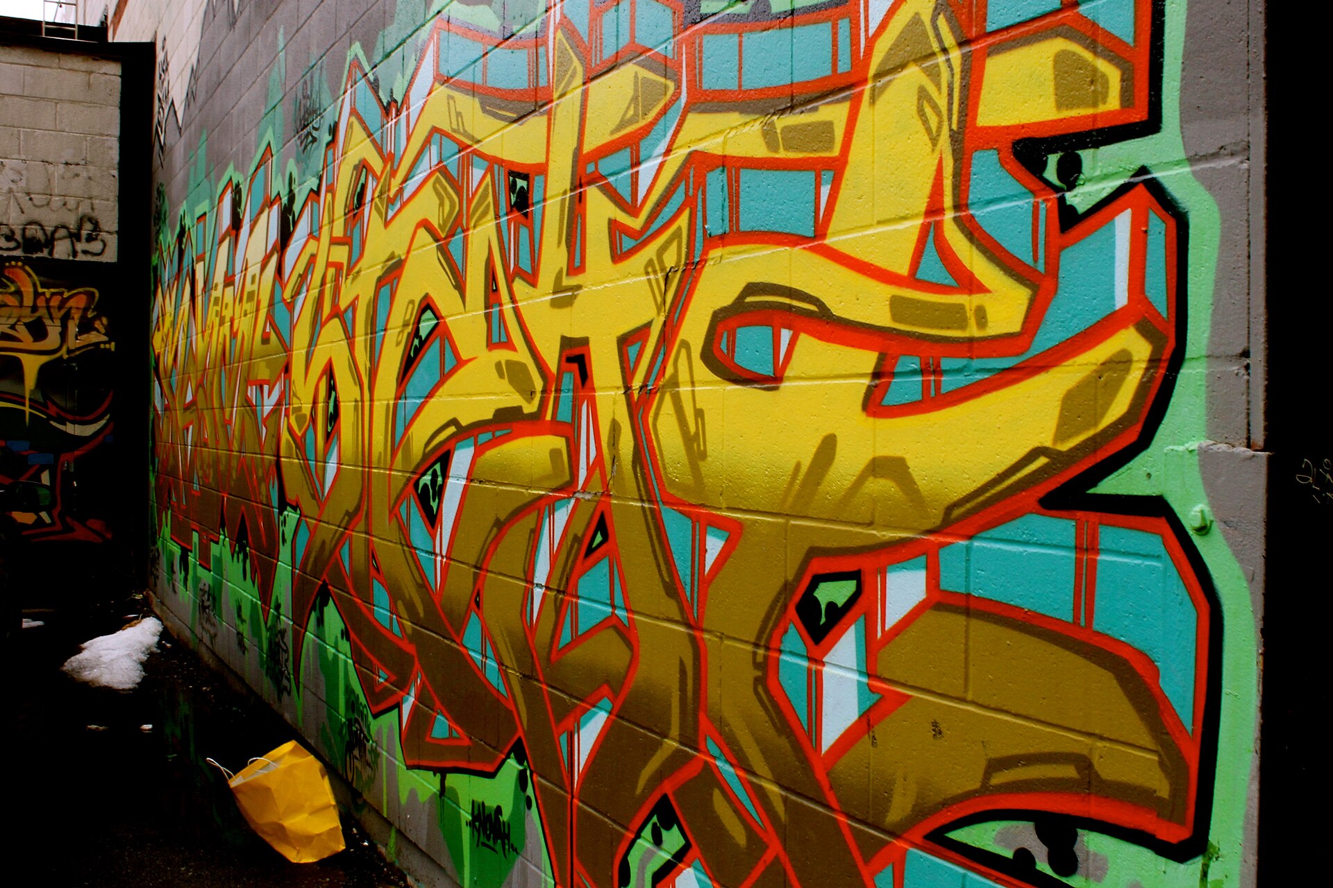 Yellow letter graffiti across a turquoise wall in Toronto's Graffiti Alley
